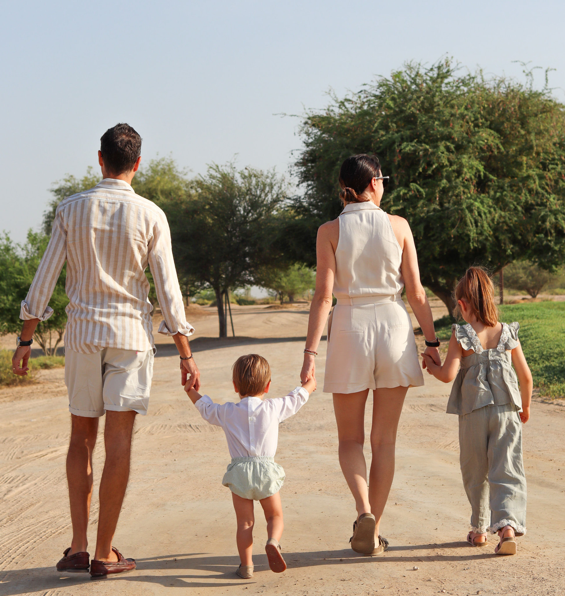 A family walking hand in hand along a sandy path in the golden evening light
